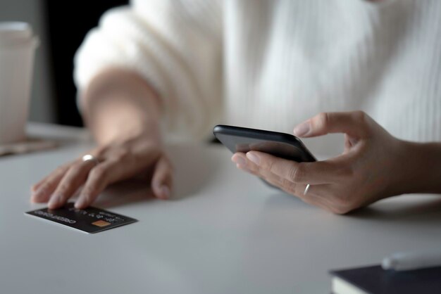 Manos femeninas usando teléfono inteligente con tarjeta de crédito en la mesa Compras en línea