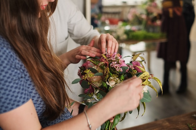 Las manos del florista recogen el ramo de la boda. florista en el trabajo