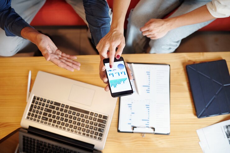 Foto manos de gente de negocios discutiendo gráficos y diagramas en la pantalla del teléfono inteligente, vista desde arriba