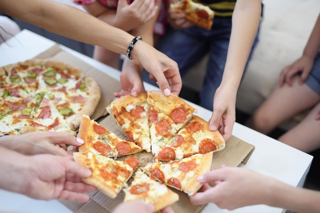 Las manos de la gran empresa toman un trozo de pizza de forma redonda