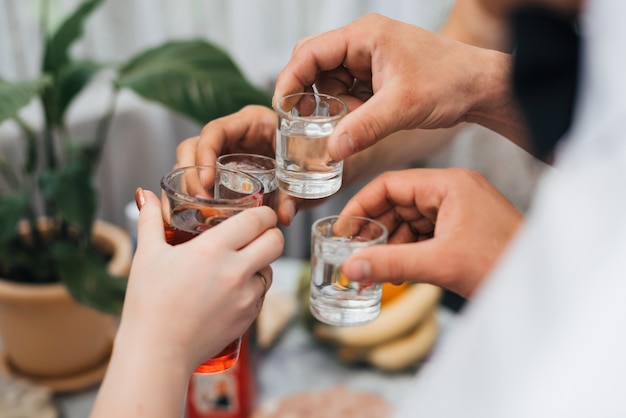 Manos de un grupo de amigos que tintinean vasos de vodka