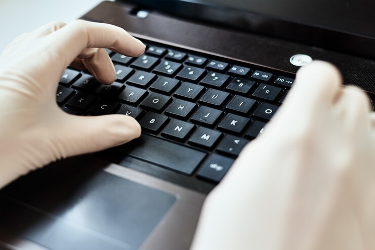 Foto manos en guantes escribiendo en el teclado del ordenador portátil. concepto de protección contra virus
