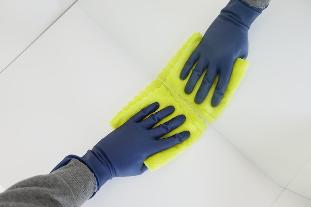 Manos en guantes de goma azules limpiando la mesa con un paño