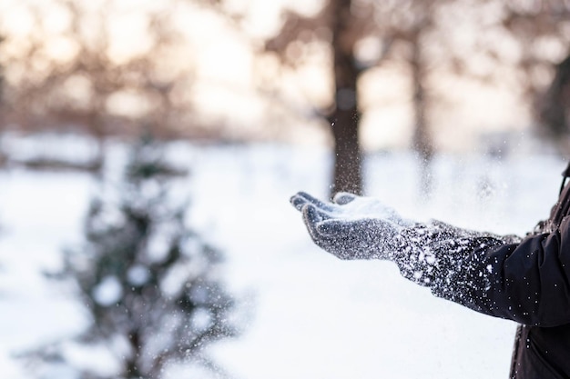 Manos en guantes grises de invierno Palma con un guante en la nieve El tipo arrojó nieve