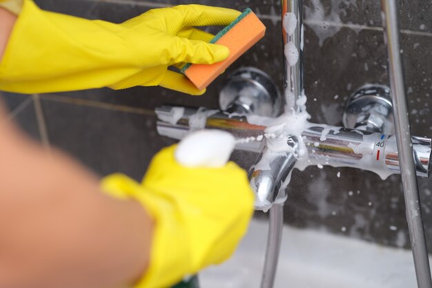 Manos en guantes lavar la batidora en el baño.