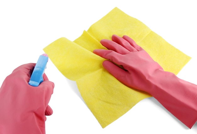 Manos en guantes limpiando la superficie con un trapo amarillo y spray aislado en blanco