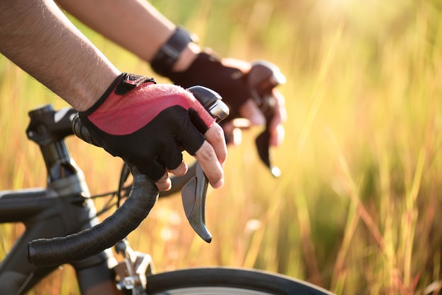 Foto manos en guantes con manillar de bicicleta de carretera. concepto deportivo y al aire libre.