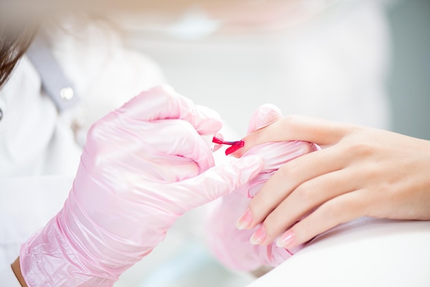 Foto las manos en guantes se preocupan por las uñas de las manos manicure salón de belleza.