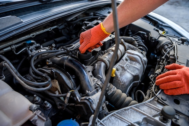 Manos en guantes protectores con motor de coche de cerca. Concepto de reparación de automóviles