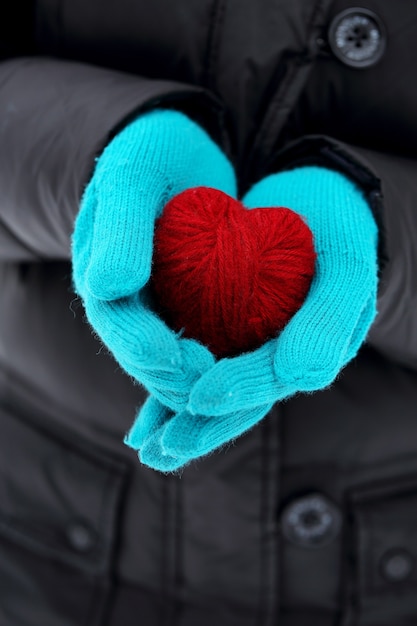 Foto manos en guantes de punto con corazón rojo