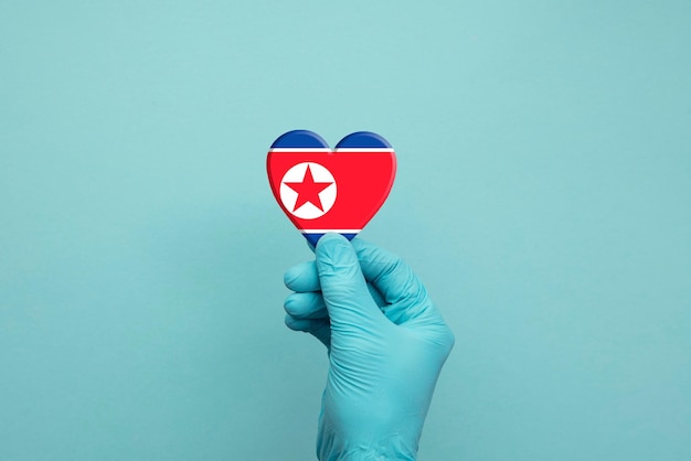 Manos con guantes quirúrgicos protectores con corazón de bandera de corea del norte