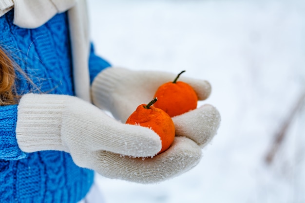 Manos en guantes sosteniendo mandarinas