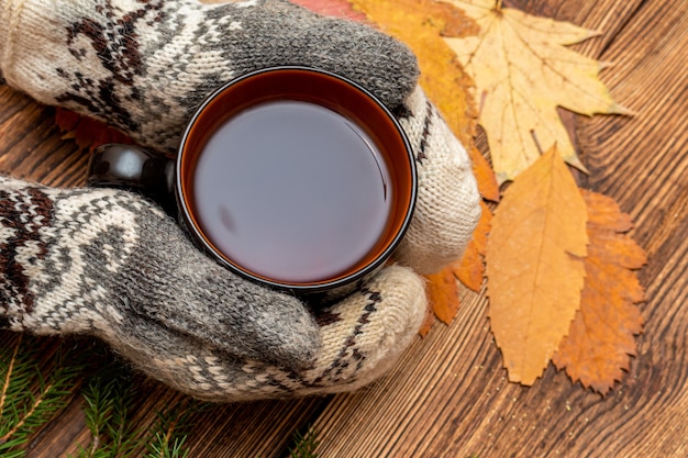 Manos en guantes sosteniendo una taza de té