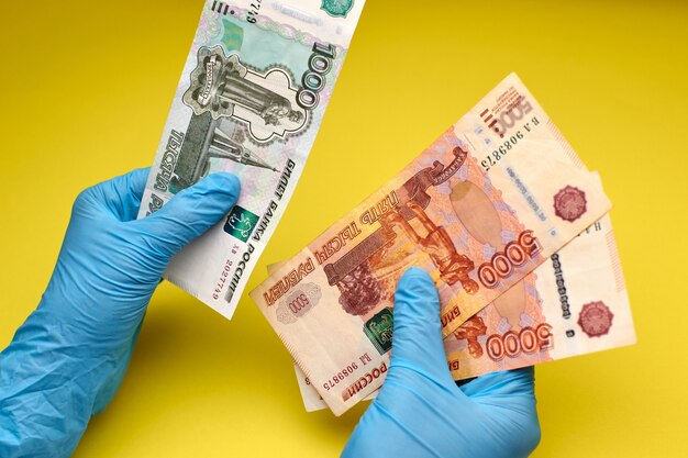 Las manos en guantes sostienen billetes