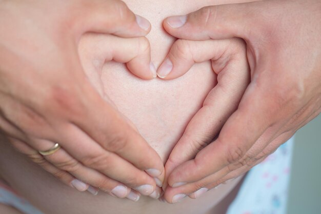 Las manos hacen corazón en el vientre