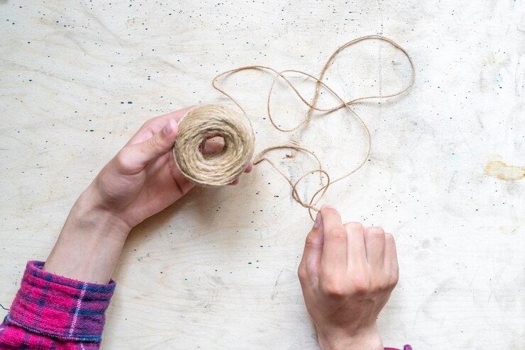 Foto las manos hacen un nudo de una cuerda gruesa con una bola de cuerda