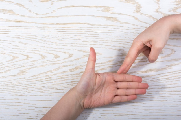 Manos haciendo gesto de piedra, papel o tijera sobre un fondo de madera