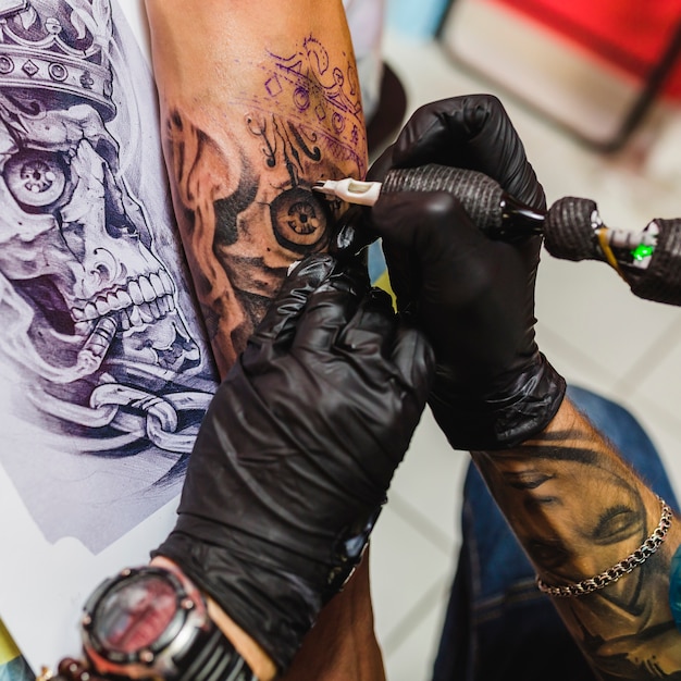 Foto manos haciendo tatuaje en la mesa con dibujo