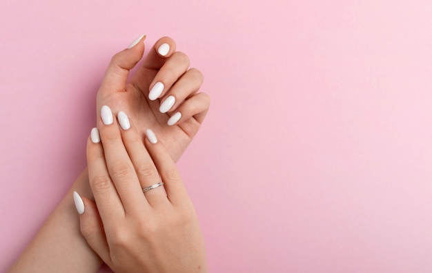 Foto manos de una hermosa mujer bien arreglada con uñas femeninas sobre un fondo rosa manicura pedicura