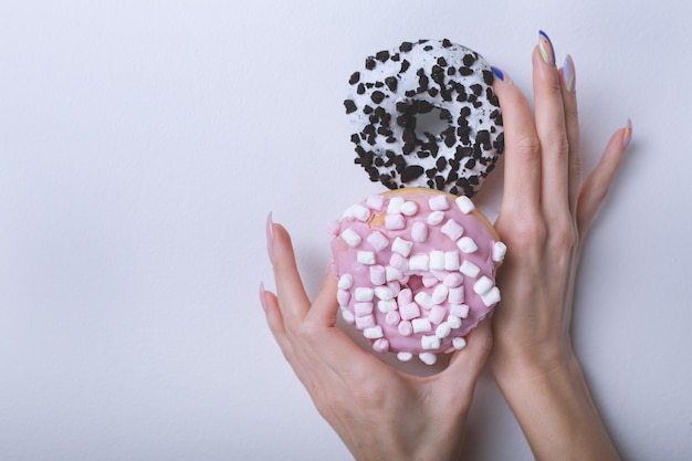 Manos hermosas femeninas con manicura de moda con donuts