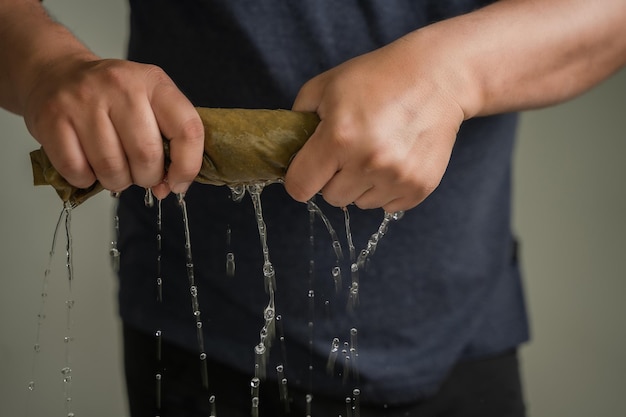 Las manos del hombre aprietan la tela mojada al aire libre gota agua apretón corto