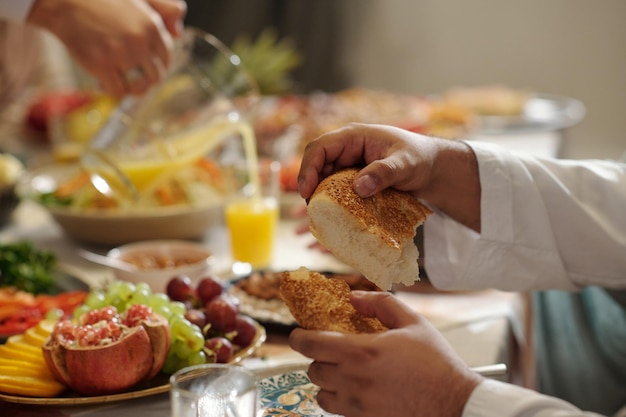 Foto las manos de un hombre arrancando un pedazo de pan durante la cena