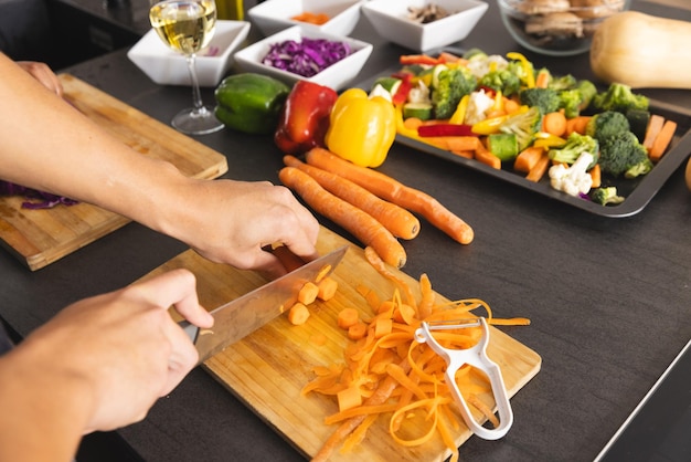 Manos de hombre biracial preparando comida, cortando zanahorias en la cocina, espacio de copia