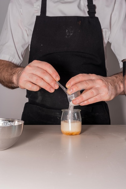 Manos de un hombre cocinando un pastel de terciopelo rojo en casa haciendo una mezcla con vinagre y bicarbonato de sodio en casa