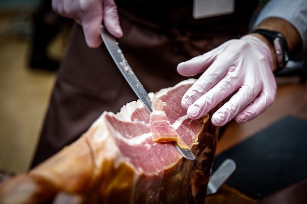 Las manos de un hombre cortan una rebanada de jamón de bellota tradicionalmente español