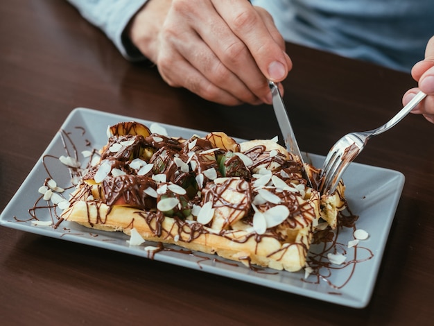 Manos de hombre cortando gofres belgas. comida y manjar dulce