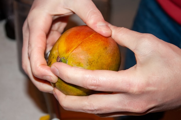 Las manos del hombre dividen el mango en rodajas