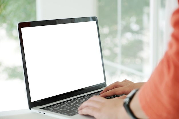 Manos del hombre escribiendo la computadora portátil con pantalla en blanco para maqueta fondo