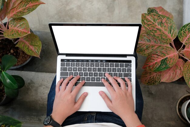 Manos del hombre escribiendo la computadora portátil con pantalla en blanco