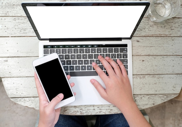 Manos del hombre escribiendo la computadora portátil y el teléfono inteligente