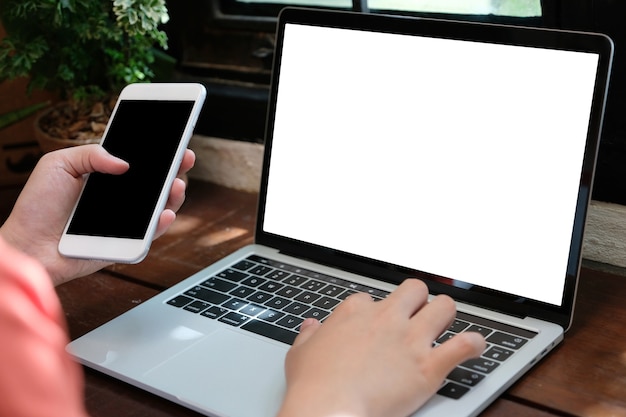 Manos del hombre escribiendo la computadora portátil y el teléfono inteligente