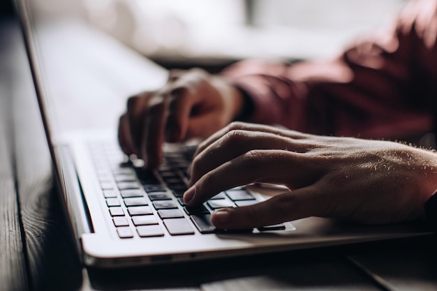 Manos de hombre escribiendo en el teclado de la computadora portátil