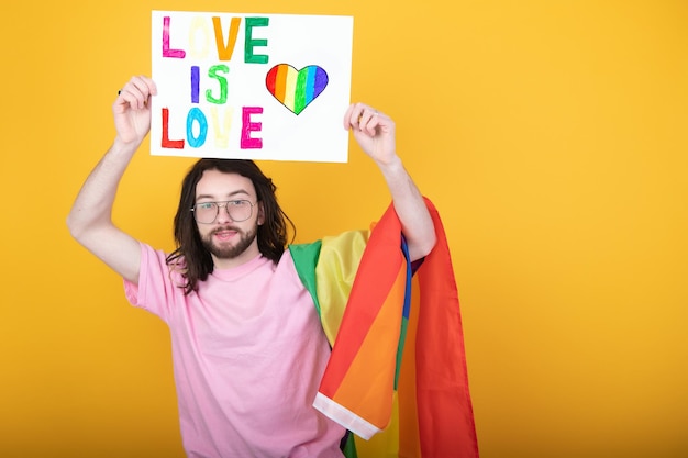 Manos de hombre gay sosteniendo la bandera lgbt en el símbolo lgbt de fondo de la bandera del arco iris