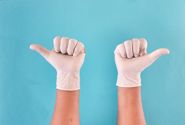 Foto manos del hombre con guantes de látex levantando el pulgar.