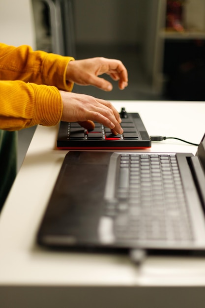 Foto las manos de un hombre haciendo ritmos desde su sofá en la mesa de café con un controlador mpd midi