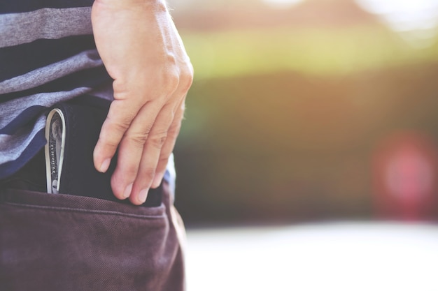 Manos de hombre hipster sosteniendo billetera con tarjetas de crédito y pila de dinero