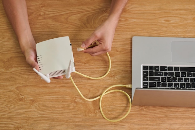 Las manos del hombre insertando el cable en el router wifi vista desde arriba