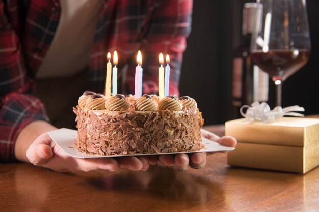 Manos de hombre joven con hermoso pastel de cumpleaños