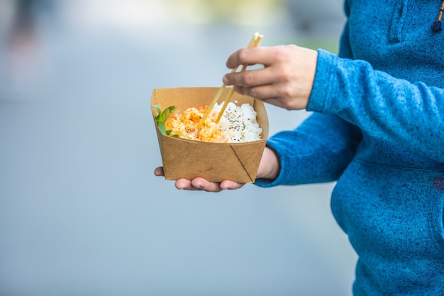 Manos de hombre joven sosteniendo el almuerzo en una caja de papel reciclado.