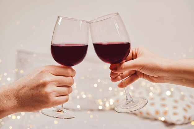 Las manos de un hombre y una mujer están sosteniendo copas de vino atmósfera romántica enfoque suave bokeh primer plano