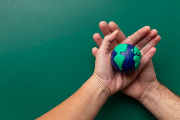 Manos de hombre y mujer sosteniendo la Tierra cuidando el planeta medio ambiente ecología humanidad