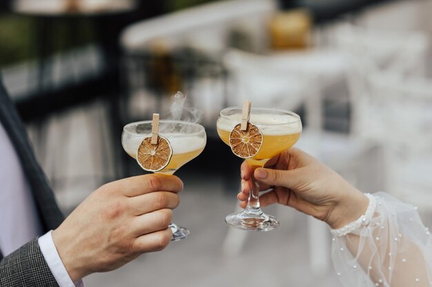 manos de hombre y mujer tintineando vasos de cócteles alcohólicos