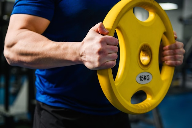 Manos de hombre musculoso con peso de mancuernas de gimnasio