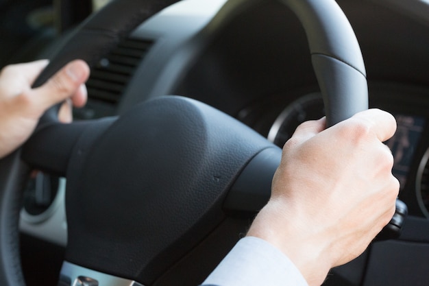 Manos de hombre de negocios en coche de lujo volante