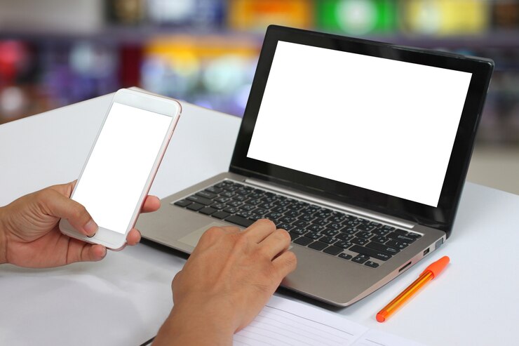 Foto las manos de un hombre de negocios que sostiene un smartphone vacío y tienen ordenador portátil en blanco del cuaderno.