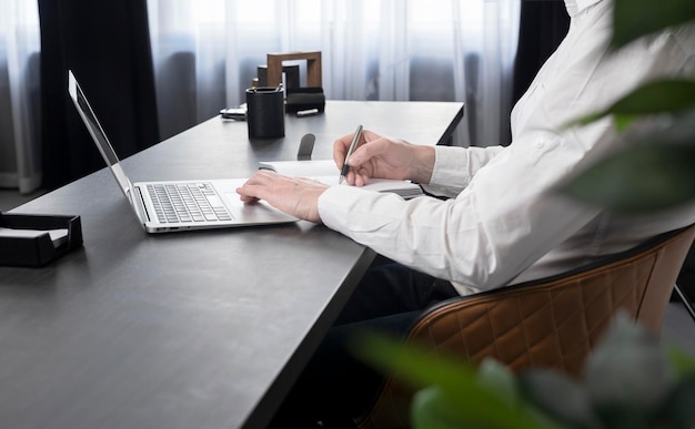 Manos de hombre de negocios tomando notas en el cuaderno y navegando por información en internet o preparándose para la corporación...